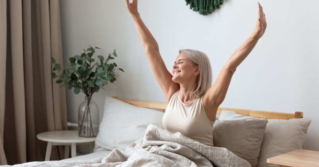 Woman with short hair waking up in bed, feeling refreshed (MODEL)