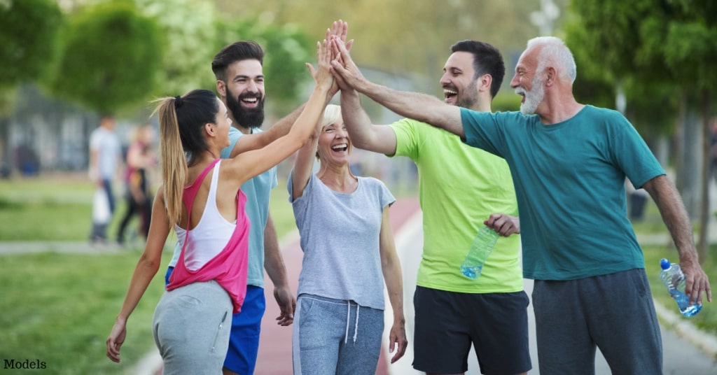 A group of various aged men and women giving each other a high five after a walk (models)