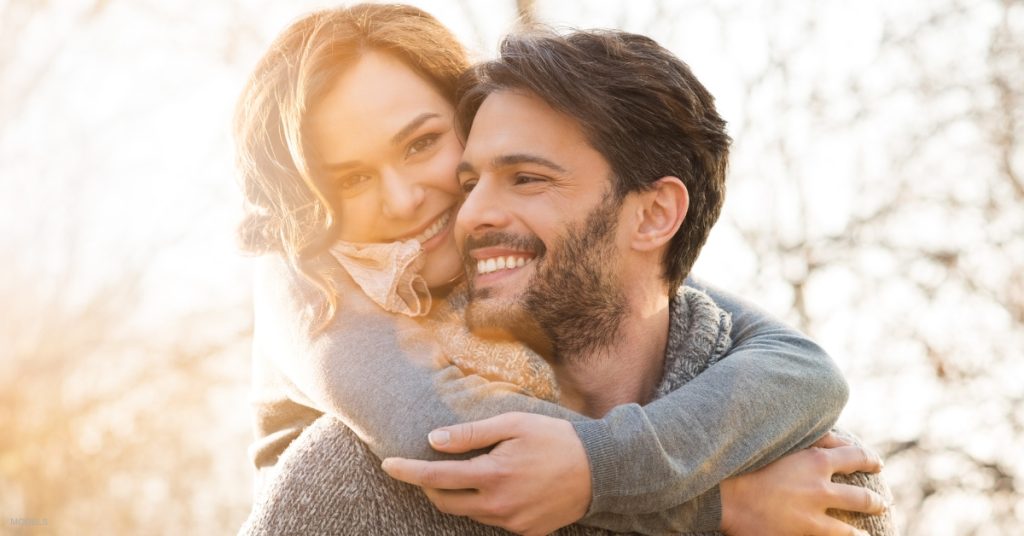 Young woman hugging man from behind (MODELS)