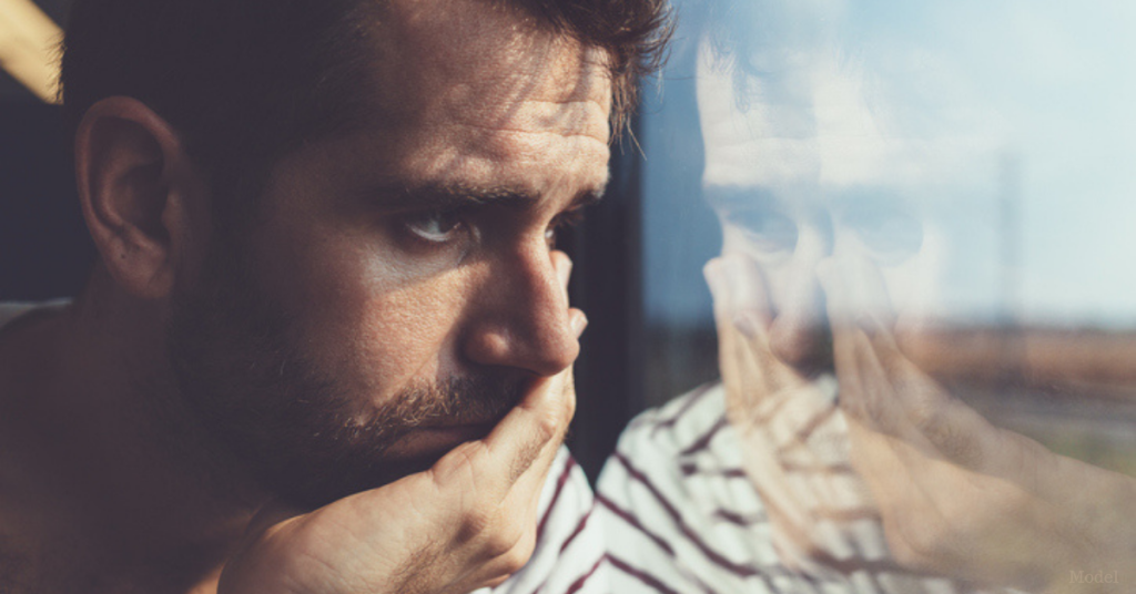 A man looking out the window concerned about the possibility of erectile disfunction (model)